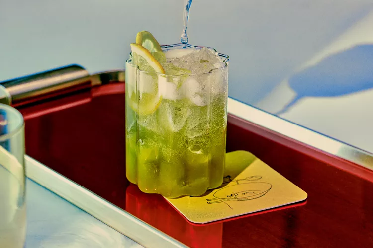 Matcha Highball cocktail in a glass, green colored with ice and lemon
