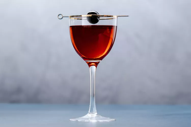 Rob Roy cocktail in a cup, in red color and a cherry
